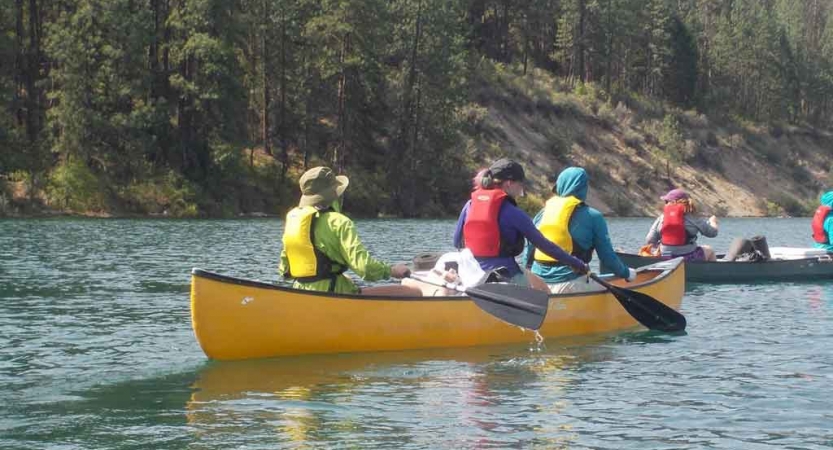 a group of students paddle canoes on a lake in washington state